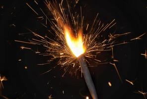 A sparkler is lit with a black background photo