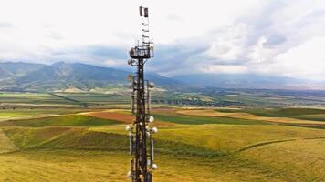 telecommunication tower in front of agricultural field and mountain range video