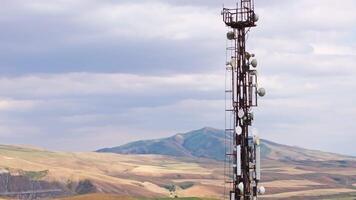 telecommunication tower in front of agricultural field and mountain range video