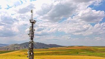 hyperlapse around telecommunication tower in front of agricultural field and mountain range video