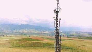 telecommunication tower in front of agricultural field and mountain range video