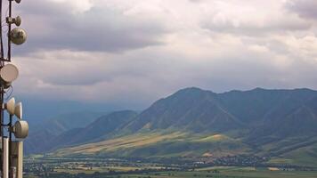 telecommunication tower in front of agricultural field and mountain range at stormy day video