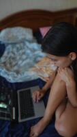 A Focused Young Woman Engaged in Her Work on a Laptop in the Comfort of a Cozy Bedroom video