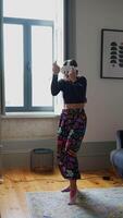 A woman joyfully dancing in colorful pants within the comfort of her own home space video