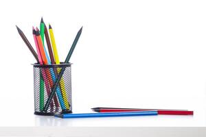 Colorful pencils arranged in a black mesh holder on a white background photo