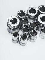 Selection of polished metallic socket wrenches arranged neatly on a white surface photo