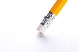 Bright yellow pencil with an eraser hovering above a blank sheet of paper in a minimalistic setting, capturing the essence of creativity and ideas photo