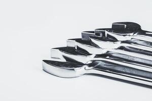 Wrenches lined up on a white surface showcasing their glossy metal finish and varied sizes ready for use photo