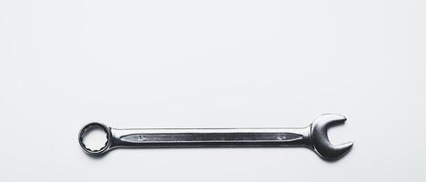 Metal wrench resting on a clean surface, ready for mechanical tasks and repairs in a workshop or garage setting photo