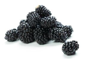 Fresh blackberries piled on a white surface, showcasing their rich color and texture, perfect for healthy snacking or culinary use photo