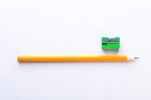 Bright yellow pencil and green sharpener arranged on a clean white surface photo