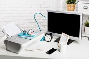 Workstation setup with printer, monitor, and desk accessories in a modern office environment photo