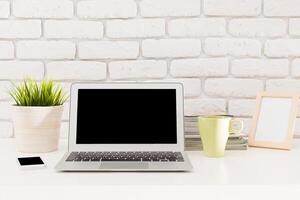 Modern workspace setup with a laptop, stationery, and plants arranged on a desk in a bright and inviting environment photo