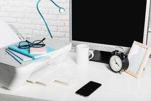 Workspace setup with printer, computer, and stationery during daylight in a modern office environment photo