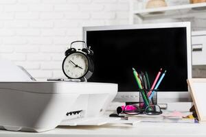 Office workspace with a clock, printer, and computer showcasing a productive environment in a well-organized setting photo
