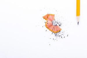Pencil shavings and a sharpened yellow pencil arranged on a clean white background for artistic presentation photo