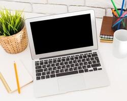 Workspace with a laptop, notebook, and cup on a desk in a bright environment photo