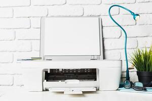 Modern printer and desk setup in a bright workspace featuring a stylish lamp and decorative plants photo