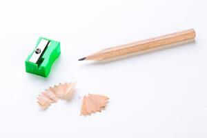 Pencil sharpener, pencil, and shavings arranged on a white surface during a stationary setup for a creative workspace photo