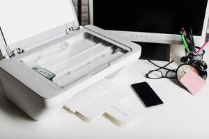Desk setup with printer, smartphone, and clock during work hours in a modern office environment photo