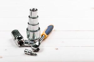 Tools arranged on a workshop table showcasing various sizes of sockets and a screwdriver for mechanical tasks photo