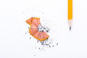 Sharpened pencil next to orange pencil shavings on white background in a creative workspace photo