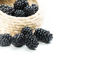 Fresh blackberries displayed in a woven basket on a white surface, showcasing the fruit's texture and color photo
