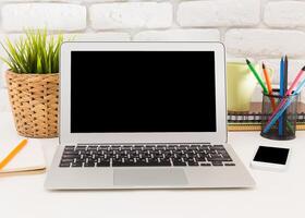 Modern workspace setup with a laptop, stationery, and plants arranged on a desk in a bright and inviting environment photo