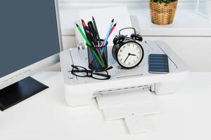 Workstation setup featuring a printer, decorative items, and organizational tools during a daytime routine photo