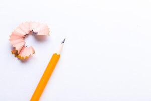 Sharpened pencil and wood shavings on a clean white surface, highlighting artistic creativity and preparation for writing photo