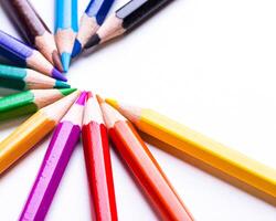 Vibrant colored pencils arranged in a circular pattern on a white surface during daylight photo