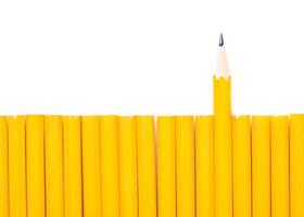 Unique arrangement of yellow pencils with one sharpened pencil standing out from the group on a white background photo