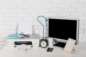 Workspace setup with printer, monitor, clock, and stationery in a modern office environment photo