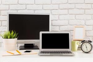 Modern workspace setup featuring a laptop, desktop monitor, and desk accessories in a minimalist environment photo