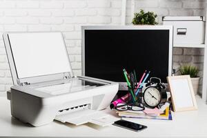 Desk clutter with printer, computer, and office supplies in a bright workspace setting photo