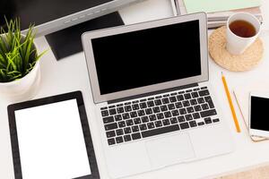 Workspace setup featuring a laptop, tablet, smartphone, and coffee during a productive afternoon photo