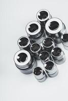 Various sizes of chrome socket wrenches arranged on a plain surface in a well-lit workspace photo