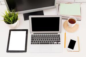 Modern workspace setup with laptop, tablet, and cozy decorative elements photo