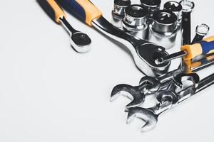 Collection of various hand tools including wrenches and ratchets on a clean surface photo