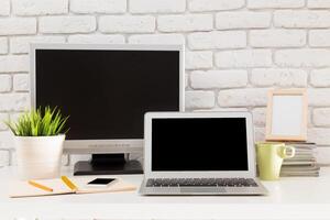 Modern workspace featuring a laptop, desktop monitor, and decorative elements in a minimalistic setting photo