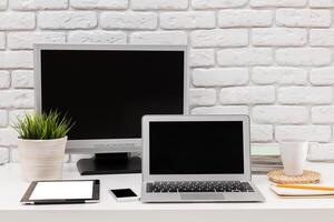 Modern workspace setup with a laptop, stationery, and plants arranged on a desk in a bright and inviting environment photo