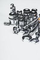 Various hand tools including sockets and wrenches arranged on a clean surface photo