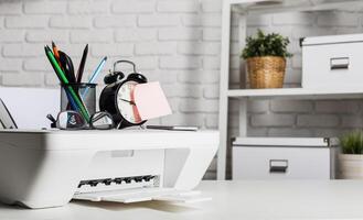 Office workspace with printer, clock, and stationery on a modern desk photo