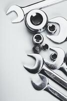 Collection of shiny metallic tools arranged on a light surface showcasing wrenches and sockets photo