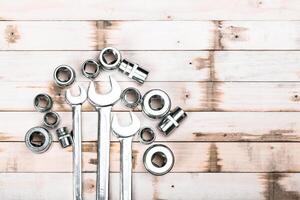 Tools arranged on a wooden surface showcase various sizes of wrenches and sockets used for mechanical work photo