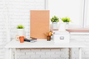Stylish workspace design featuring plants, stationery, and a corkboard on a clean desk near a window photo