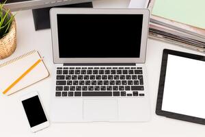 Work station overview with laptop, tablet, smartphone, and stationery on a clean desk photo
