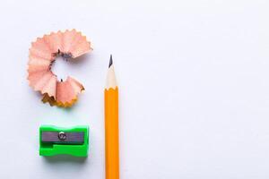 Bright orange pencil with sharpener and shavings on a clean surface photo