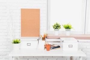 Modern workspace design featuring a corkboard, plants, and organized stationery in a bright, minimalistic setting photo