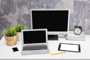 Modern workspace setup featuring multiple devices and plants on a textured desk photo